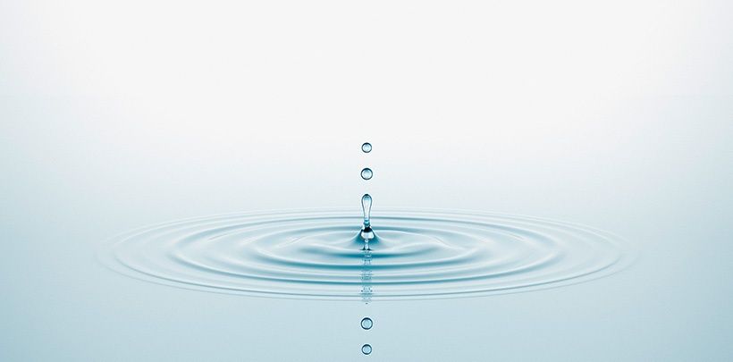 Einzelne Tropfen fallen in stilles Wasser als Symbolbild für Hänseler Swiss Pharma Liquid Solutions